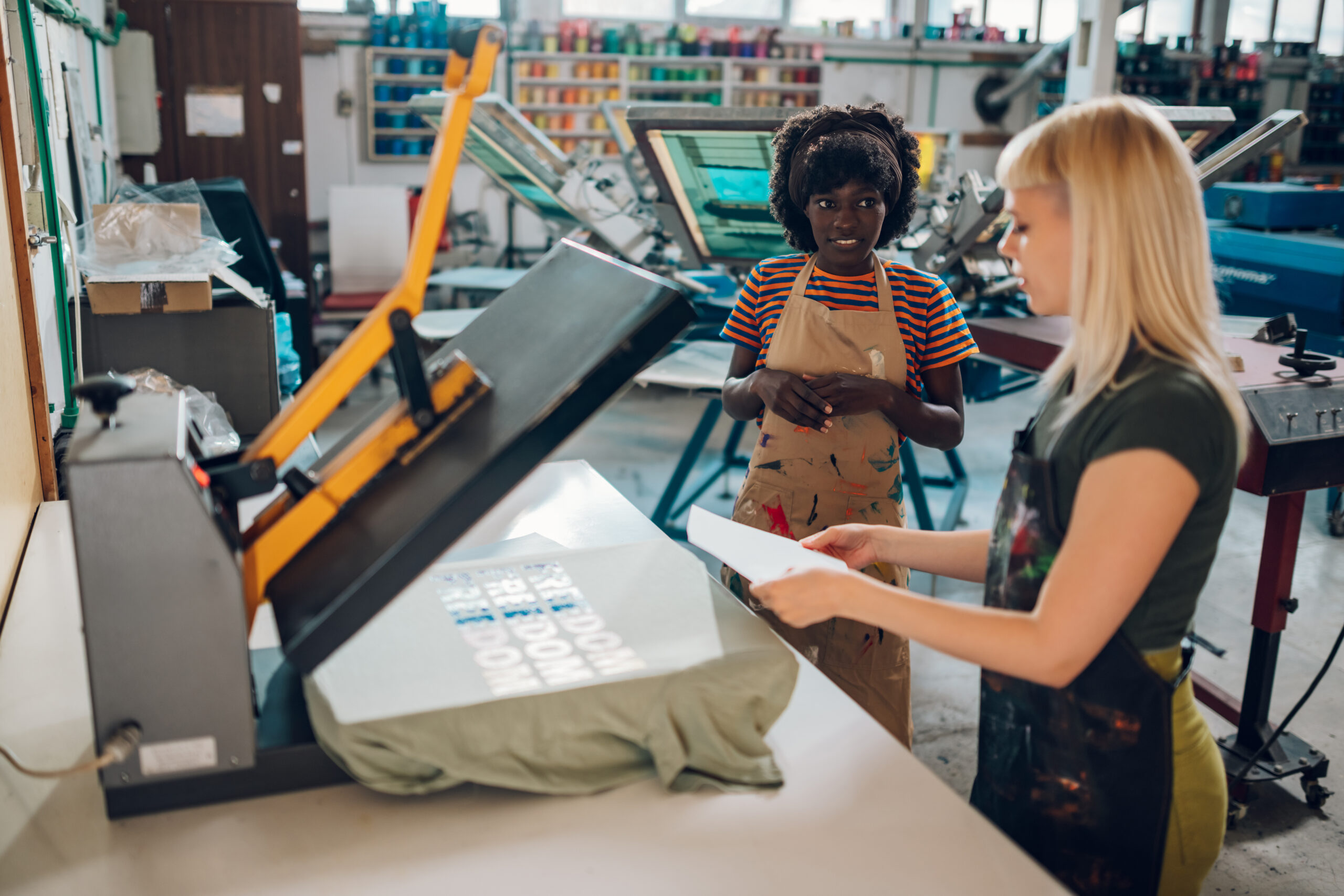 Shop workers using dye-sublimation and heat transfers with heat press