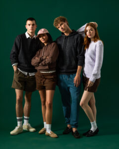 Lane Seven Nantucket Collection models wearing plush, textured knit hoodies and sweaters in a fashion photoshoot with green backdrop.