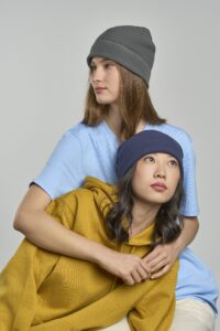 Two women wearing Atlantis Headwear BIRK beanies in gray and navy with casual hoodies and T-shirts in a studio photoshoot.