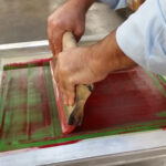 A printer in action demonstrating the essential role of squeegee angle and pressure in achieving crisp, consistent prints. Photo courtesy of International Coatings