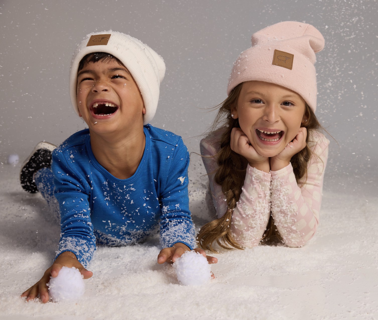 Children playing in snow wearing Woolx Merino wool base layers and hats.