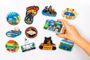 Assorted promotional souvenir magnets featuring travel destinations, illustrating custom merchandise and branded promo product options.