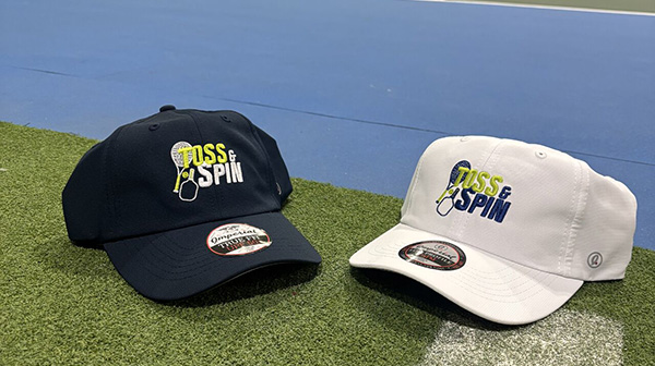 Imperial Toss & Spin co-branded performance hats displayed on indoor pickleball court highlighting official headwear partnership