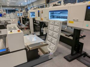DTF printing machines producing gang sheets in a garment decoration facility with automated workflow