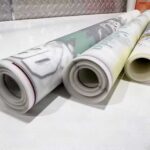Rolled DTF gang sheets on transfer film showing multiple designs prepared for heat transfer production