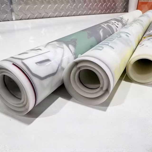 Rolled DTF gang sheets on transfer film showing multiple designs prepared for heat transfer production