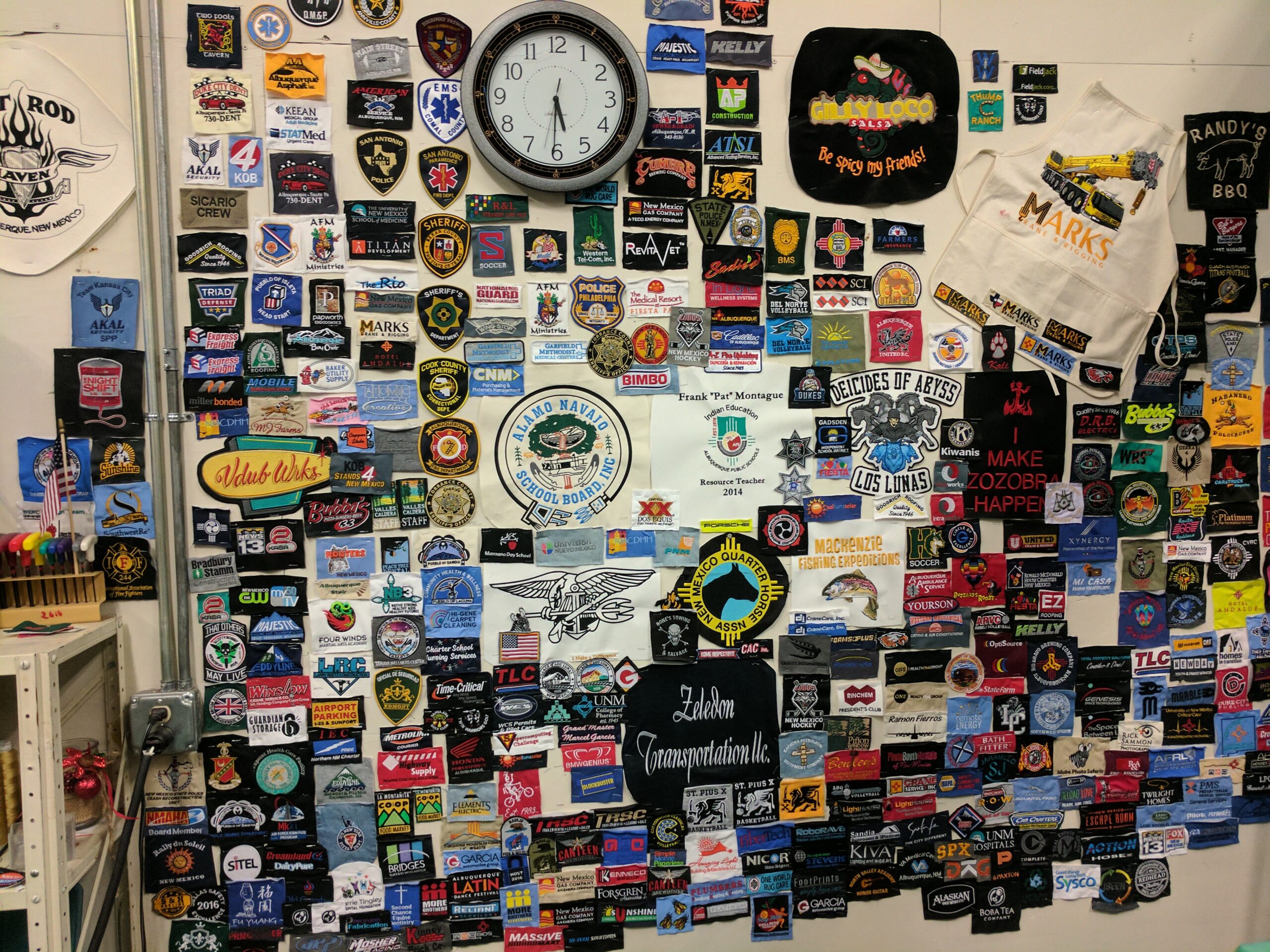 Wall displaying hundreds of embroidered logo samples used to evaluate embroidery digitizing quality, stitch density, lettering clarity and design execution.