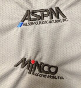 Embroidered company logos demonstrating successful small-text digitizing techniques that preserve lettering clarity and registration on knit garments.