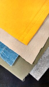 Assorted fabric swatches illustrating how different material constructions influence embroidery density, distortion, stabilization and stitch performance.