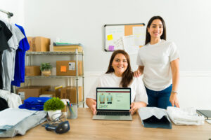 Apparel decorators manage an online print-on-demand webstore while preparing custom T-shirts for ecommerce fulfillment and on-demand apparel production.