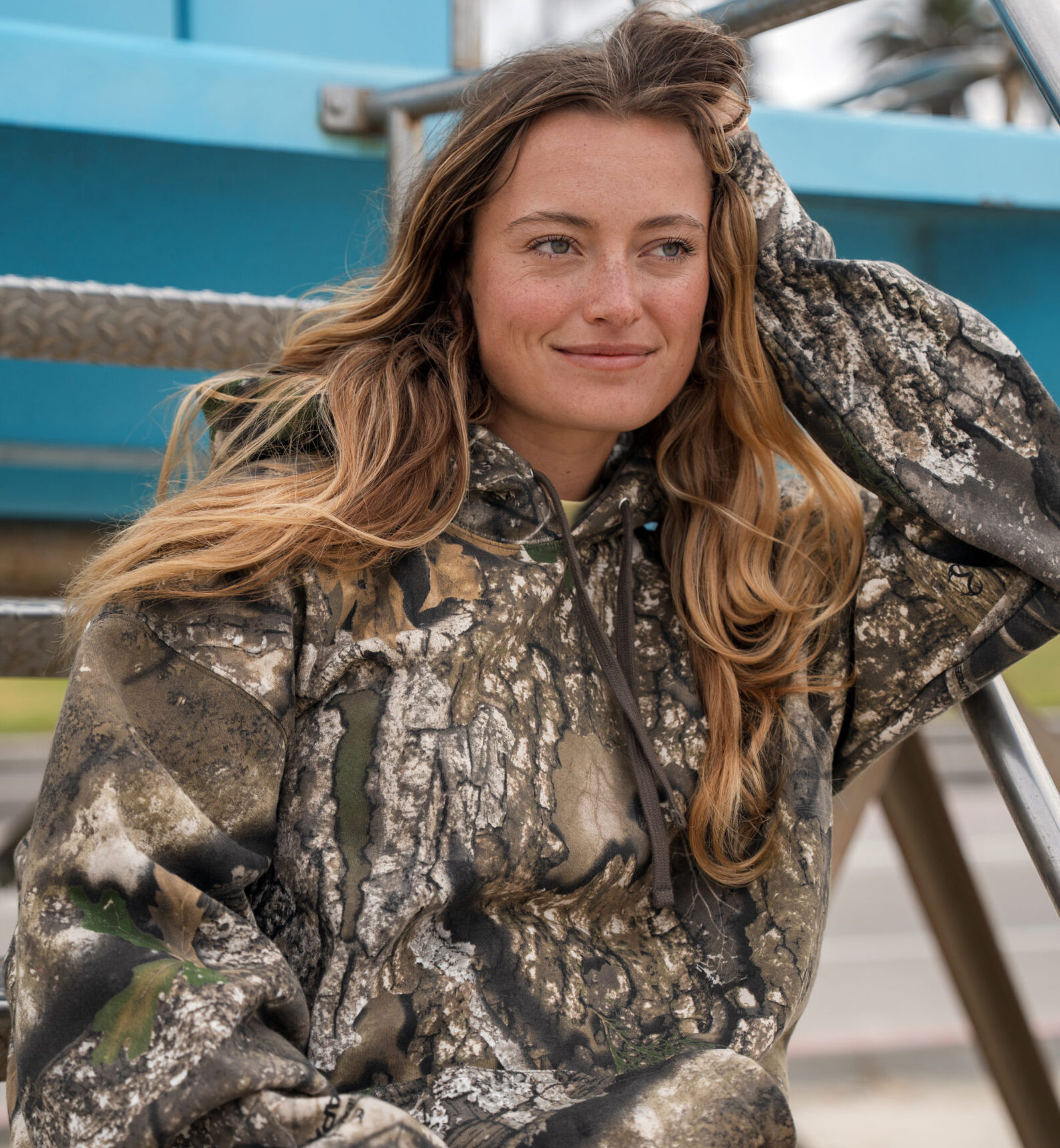 Model wearing Independent Trading Co.'s IND4000 Heavyweight Hooded Pullover in the officially licensed Realtree APX camouflage pattern.