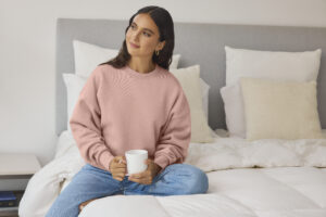 Model wearing Next Level Apparel Women's Heavyweight Fleece Sweatshirt in desert pink, featuring an oversized fit and premium blank apparel designed for decoration and everyday wear.