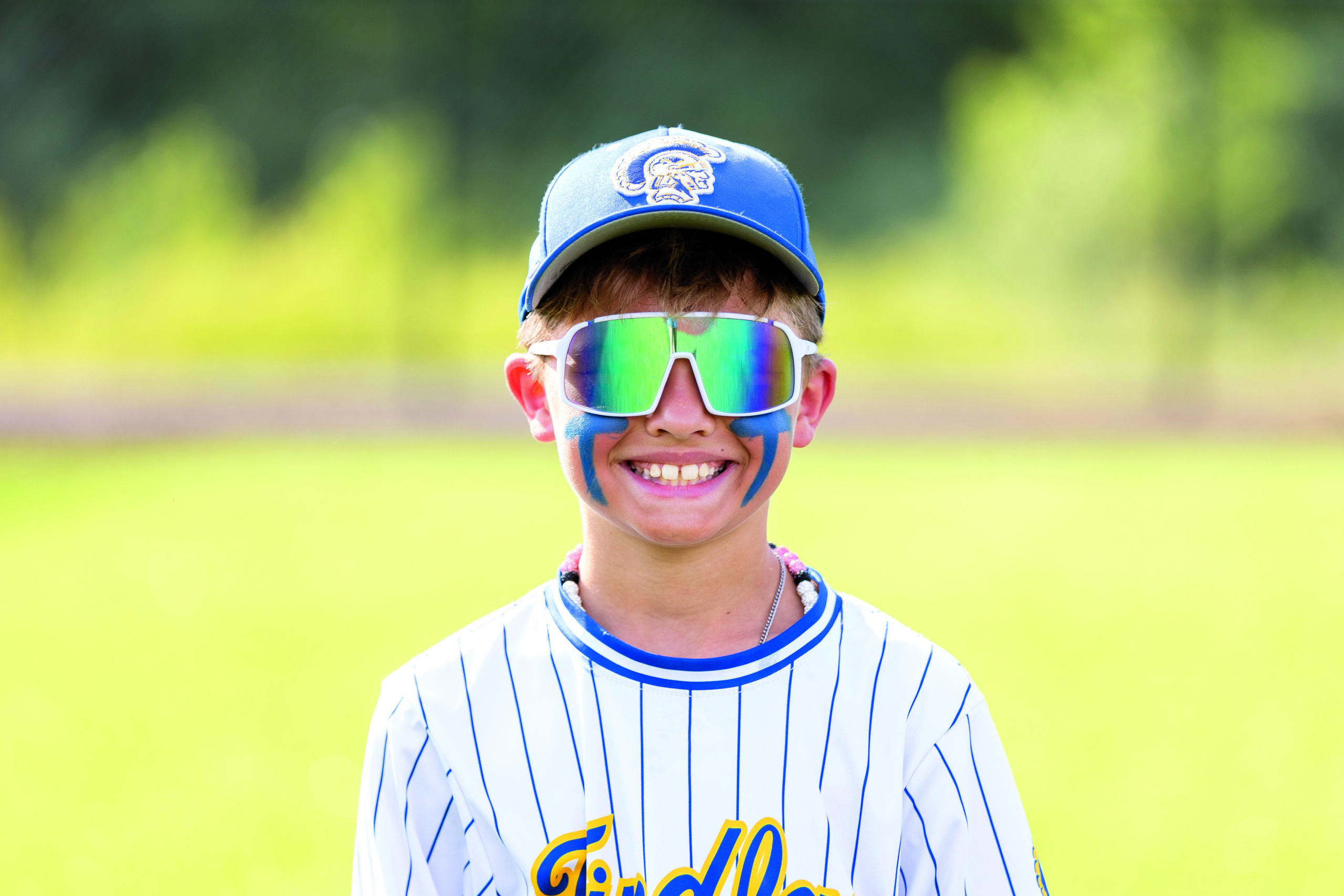 Young baseball player wearing a decorated Pukka team headwear cap with embroidered logo and performance sunglasses