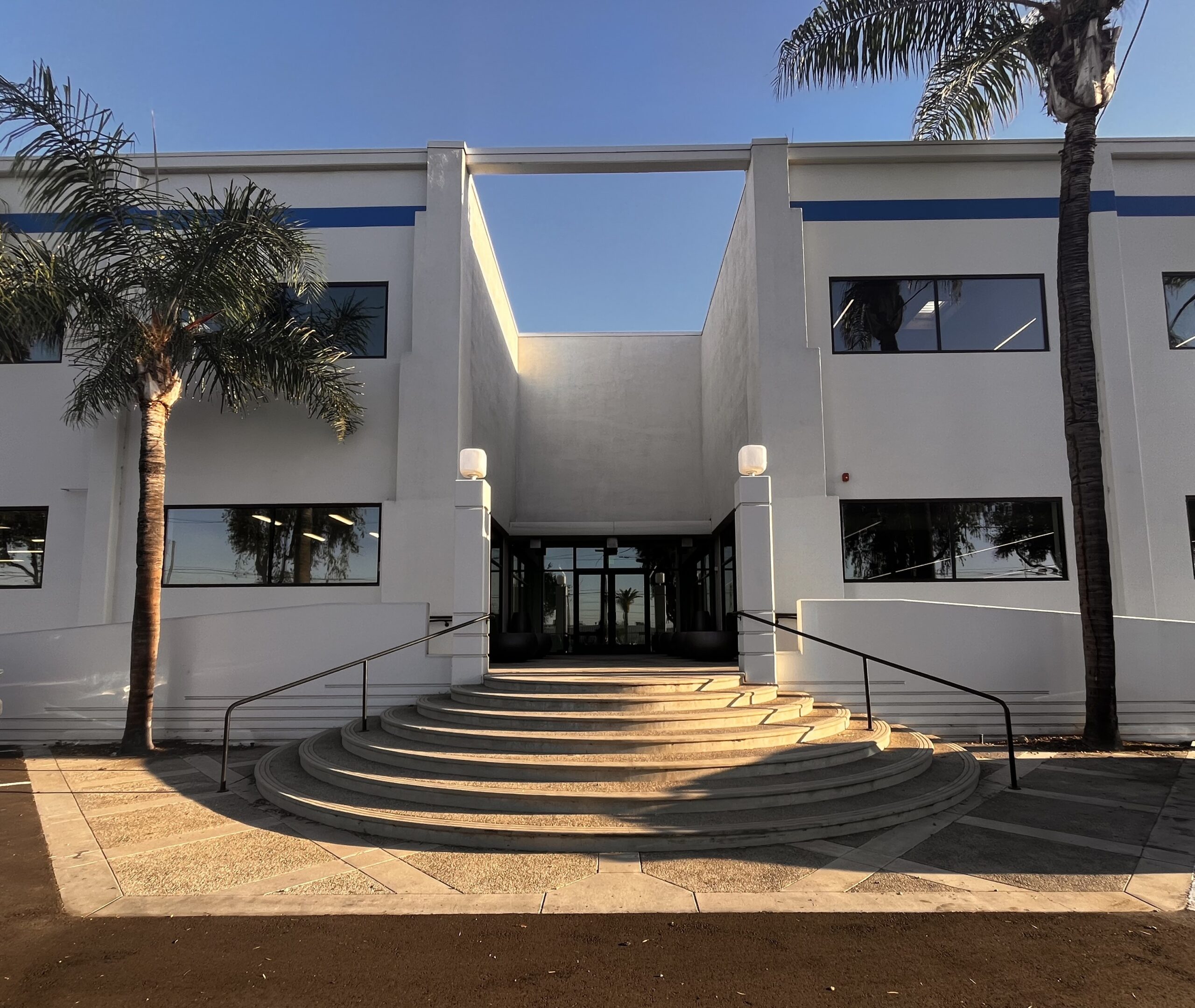 Front entrance of A4's new headquarters and West Coast distribution center in Vernon, California, featuring a white building and curved staircase.
