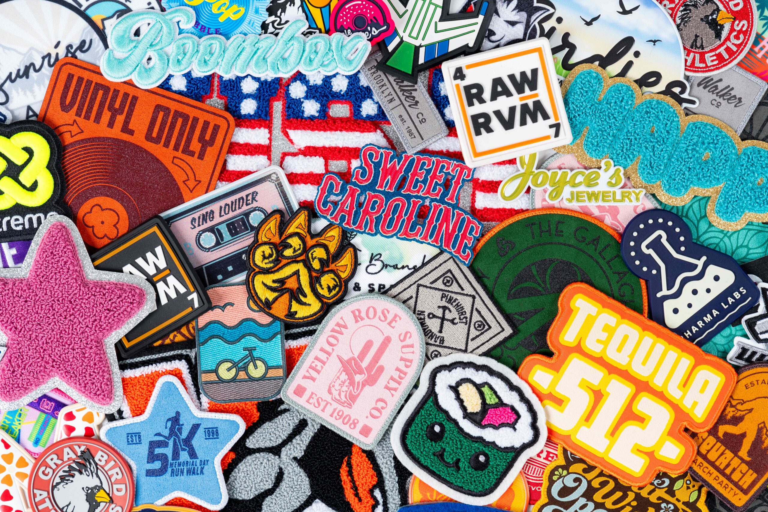 Assortment of colorful custom embroidered and specialty patches featuring logos, lettering, stars, animals and decorative graphics.